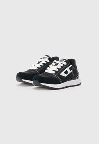 Fekete sneakers fehér fűzőkkel és díszítésekkel, velúr és hálós textúrák keverékével, vastag gumitalppal és kerek orral.