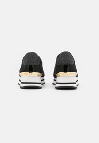 Czarne buty sportowe z teksturowaną cholewką, białą i czarną paskową podeszwą środkową oraz złotym akcentem na pięcie z napisem "Michael Kors".