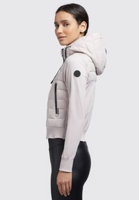 Hellrosa, taillierte Jacke mit Kapuze, die über eine gesteppten Textur am Körper, gerippte Bündchen und eine Reißverschlusstasche an der Seite verfügt.