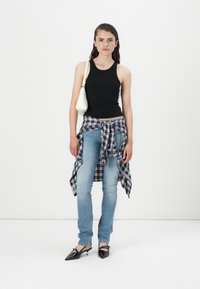 Črna rebrasta majica brez rokavov, svetlobluje skinny jeans, modra karirana srajca zavezana okoli pasu in črne ženske čevlje s pointed-toe. Bela torbica na rami.