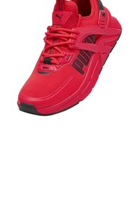 Czerwone sportowe sneakersy z siateczkowym wierzchem, czarnymi akcentami i teksturowaną podeszwą. Posiadają wyraźne logo oraz sznurowanie zapewniające bezpieczne dopasowanie.