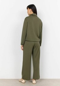 Set di abbigliamento da casa verde oliva composto da una maglietta a maniche lunghe e pantaloni a gamba larga. Tessuto morbido con una vestibilità comoda, cuciture minime e senza dettagli visibili.