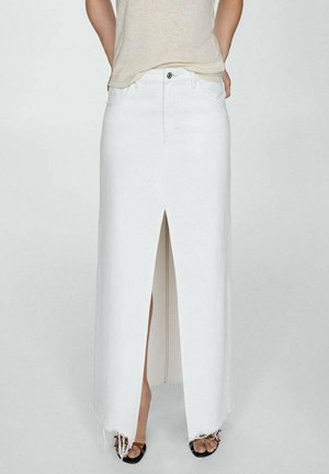 Jupe maxi en denim blanc avec une fente frontale, un ourlet effiloché, des passants de ceinture et un design standard à cinq poches, associée à un haut beige et des sandales noires.