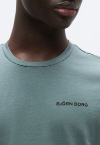 Ανοιχτό πράσινο βαμβακερό t-shirt με στρογγυλή λαιμόκοψη και κοντά μανίκια, με το κείμενο "BJÖRN BORG" σε μαύρο χρώμα στο στήθος. Ομαλή υφή.