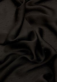 Czarna tkanina o teksturowanej powierzchni, z małymi, równomiernie rozmieszczonymi czarnymi koralikami. Materiał ma miękką, zwiewną strukturę.