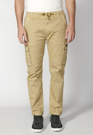 Pantaloni cargo kaki cu talie elastică, șnur de ajustare, buzunare laterale și un design al piciorului ajustat. Realizați dintr-un material de bumbac durabil.
