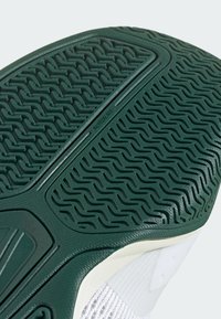 Ingrandimento di una suola di sneaker verde con modelli di grip texture e il marchio "ADIWear" vicino al centro.