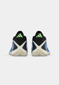 Zapatillas deportivas azules con detalles negros, tacón texturizado y suela de goma blanca. Detalles verdes en la parte del tacón y patrones triangulares en la parte superior.