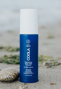 Blaues Sprühfläschchen mit weißem Deckel, beschriftet mit "COOLA Erfrischendes Wassernebel-Sonnenschutzmittel", 50 ml, mit SPF 18, alkoholfrei, biologisch.