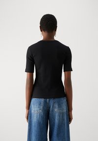 Svart randig t-shirt med kort ärm och rund hals, ihopparat med ljusblåa löst sittande jeans med bakfickor och en urtvättad look.