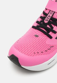 Baskets de sport roses avec une tige en maille, des lacets noirs et une semelle blanche. Présente de subtils accents noirs et le nom de la marque sur le côté.