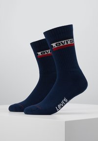 Calcetines de algodón azul marino tipo crew con textura acanalada, que presentan un logo blanco y rojo de "Levi's" y una franja de acento roja cerca de la parte superior.
