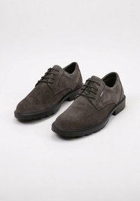 Zapatos de hombre de ante gris oscuro con cordones y suelas negras, posicionados uno al lado del otro sobre un fondo blanco.