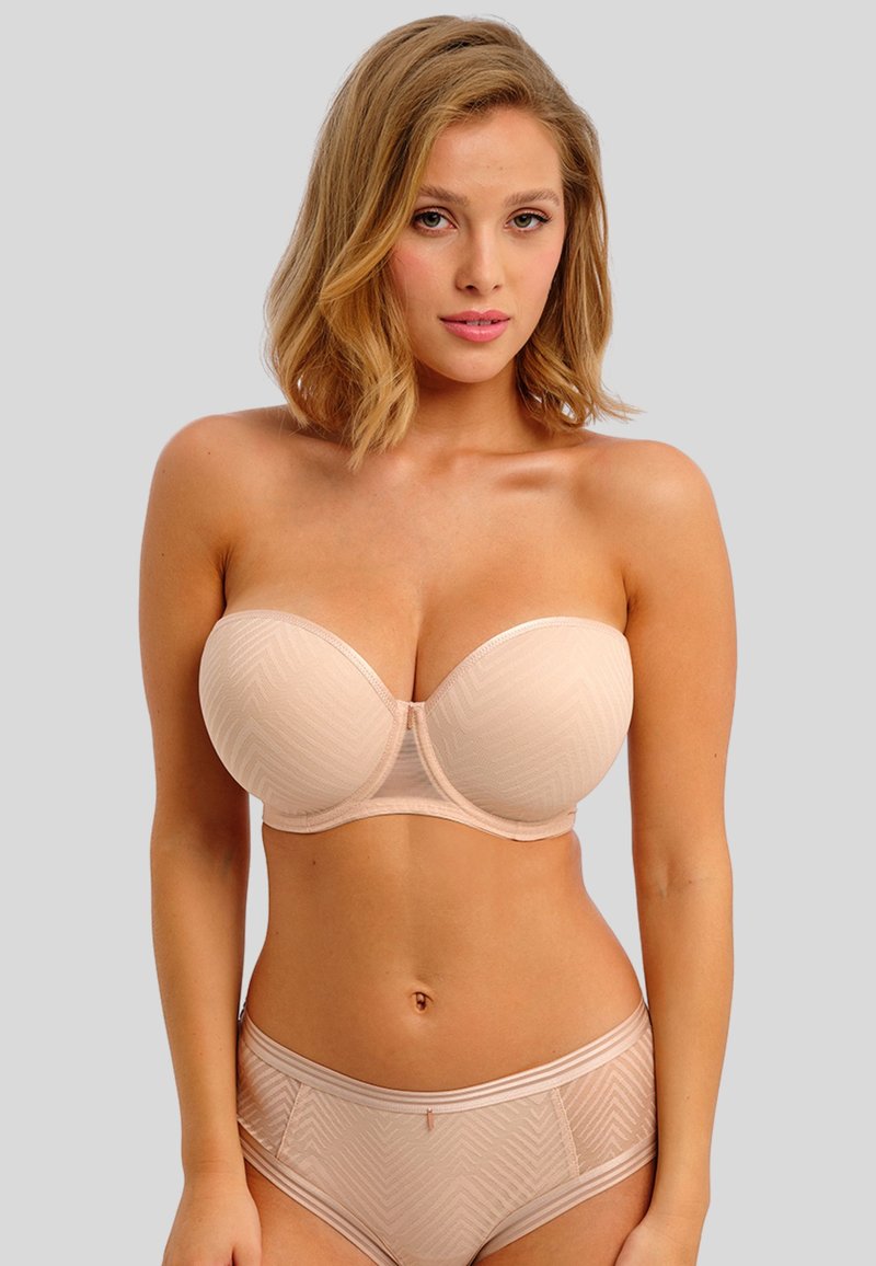 Beige strapless bh met een getextureerd geometrisch patroon, met onderdraad ondersteuning, en bijpassende slip met een vergelijkbaar patroon en afwerking.