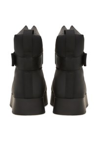 Crne gležnjače od glatkog sintetičkog materijala, s visokim dizajnom, elastičnim trakama i debelim đonom.