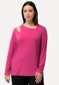 Maglietta a maniche lunghe di colore rosa acceso con scollatura tonda, caratterizzata da un taglio asimmetrico sulla spalla e una texture di tessuto morbida e liscia.