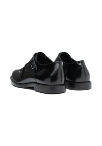 Zwarte leren schoenen met een ronde neus, een gladde textuur en twee verstelbare gespen. Beschikt over een lage hak en een rubberen zool.