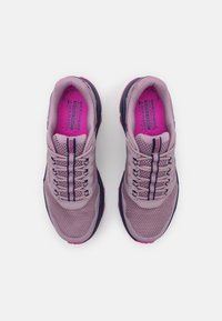 Baskets de sport en mesh violet clair avec des détails texturés, des accents sombres contrastants, des lacets et une semelle intérieure rose arborant une marque.