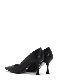 Tacones altos de cuero negro con un diseño de punta afilada y delgados tacones de aguja, que presentan un detalle recortado y sutiles acentos dorados.
