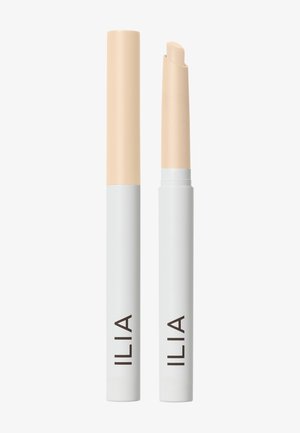 Deux sticks correcteur ILIA sont debout sur un fond blanc ; l'un avec le capuchon, l'autre sans, dévoilant le produit à l'intérieur.