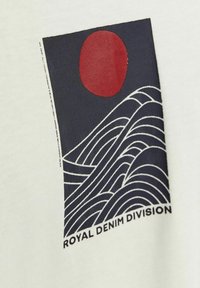 White fabric featuring a graphic print with a red circle and navy wavy lines. Text "ROYAL DENIM DIVISION" in bold black letters at the bottom.