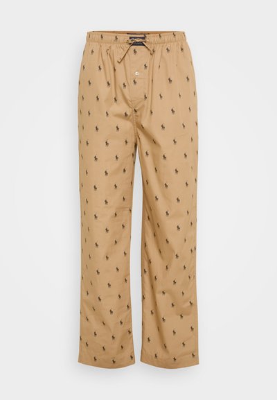 Beige bukser med en afslappet pasform, der har en snor i taljen og små sorte hestemotiver over det hele. Glat stof og lige ben.