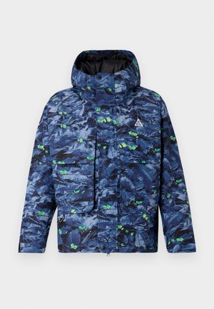 Blau-grün gemusterte Steppjacke mit Kapuze, ausgestattet mit einer Fronttasche, Reißverschluss und strukturiertem Stoff, der Blättern ähnelt.
