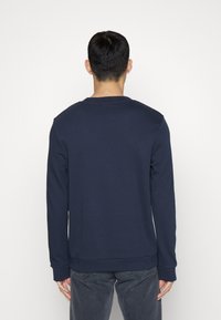 Felpa blu navy con maniche lunghe, polsini a costine e collo tondo, realizzata in un tessuto morbido e testurizzato. Design minimalista; senza fantasie.