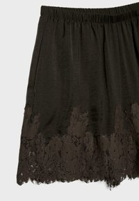 Pantaloncini neri con vita elastica e bordo in pizzo floreale lungo l'orlo, mostrati su uno sfondo semplice.