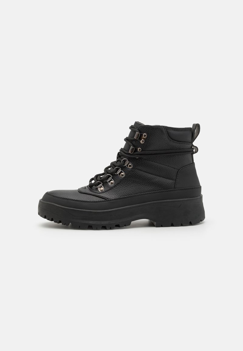 Bottines noires en cuir texturé, dotées d'œillets en métal, de lacets épais et d'une semelle en caoutchouc chunky avec un motif de crantage.