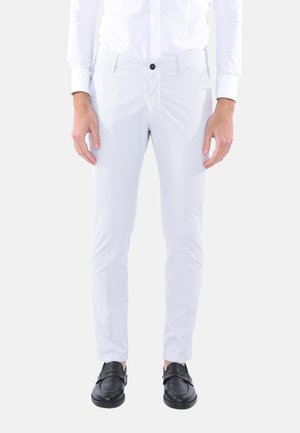 Pantaloni slim-fit grigio chiaro realizzati in tessuto morbido. Presentano una chiusura frontale con bottone e tasche laterali. Indossati con scarpe nere.