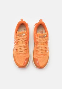 Un paio di scarpe sportive di un vivace arancione con lacci, suole bianche e tessuto in mesh traspirante viste dall'alto su uno sfondo bianco.