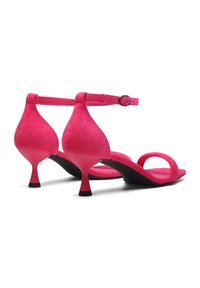 Roze suède haksandalen met een open teen, verstelbare enkelband en zwarte rubberen zool. Kenmerkt zich door een unieke, gebogen hakontwerp.