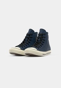 Hoge sneakers van gladde marineblauwe leer met zwarte veters, crème rubberen zolen en een ronde neus; heeft een logo label aan de zijkant.