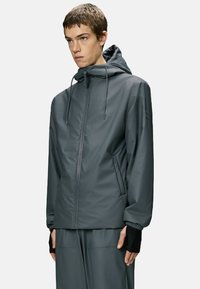 Waterbestendig jack met capuchon in donkergrijs, voorzien van verstelbare trekkoorden, ritssluiting aan de voorkant en elastische manchetten. Gladde textuur, minimalistisch ontwerp.