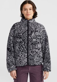 Veste polaire noire et blanche avec des motifs géométriques abstraits, col montant, fermeture éclair à l'avant et poche poitrine zippée. Texture douce.