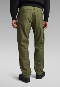 Cargo-Hosen aus olivgrünem Material mit mehreren Seitentaschen, einer leicht taillierten Passform und einem Taillenbund, der das Markenlabel zeigt.