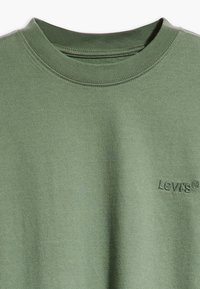 Grön bomullst-shirt med rund halsringning och broderad "Levi's"-logotyp på framsidan, med en mjuk textur och en enfärgad design.