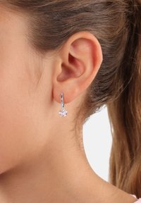 Orecchini a cerchio in argento con un ciondolo a forma di farfalla rosa; presentano un metallo lucido, un design delicato e una leggera brillantezza sulle ali della farfalla.
