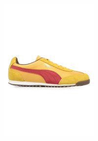 Sneaker sportivo giallo con accenti rossi, superiore in suede texturizzato e sintetico, suola bianca e lacci piatti. Presente il distintivo logo PUMA.