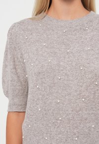 Light gray knit sweater with short sleeves, featuring a textured pattern and small pearl-like accents scattered across the fabric.