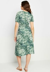 Grünes Blumendruckkleid mit kurzen Puffärmeln, taillierter Taille und ausgestelltem mid-length Rock; gefertigt aus einem glatten, leichten Stoff.