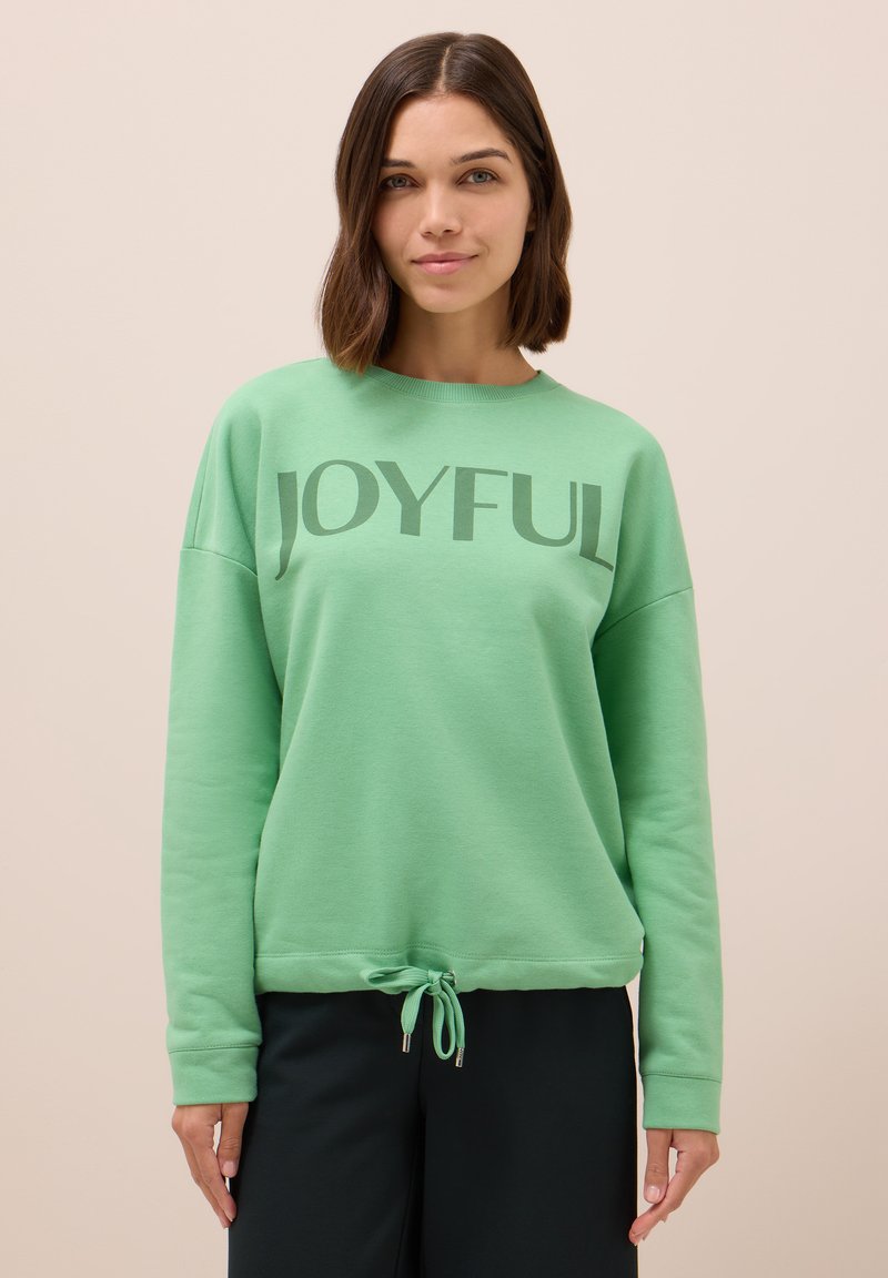 Sudadera verde claro con el texto "JOYFUL" en un tono más oscuro, puños acanalados y cintura con cordón para un ajuste ajustable.