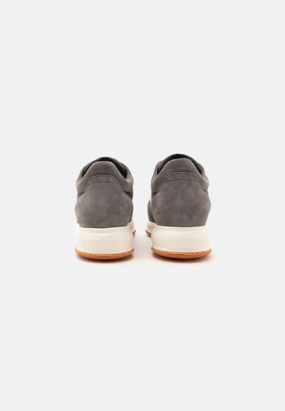 Paire de baskets en daim gris avec semelles intermédiaires blanches et semelles extérieures en caoutchouc marron clair, vues de dos sur un fond blanc uni.