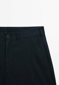 Pantalon bleu marine foncé avec fermeture avant par bouton et fermeture éclair, passants de ceinture, et poches latérales inclinées, sur fond blanc.