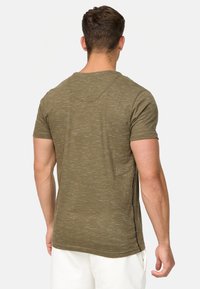 Tricou bej cu mânecă scurtă, cu un design texturat, heathered. Prezintă un gât rotund și detalii pe cusăturile laterale.