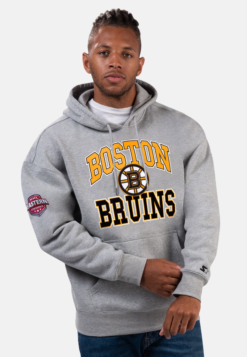 Grauer Kapuzenpullover mit "BOSTON BRUINS" in gelber und schwarzer Schrift, einem Logo und einem Ärmel-Patch. Der Stoff wirkt weich und hat eine lockere Passform.