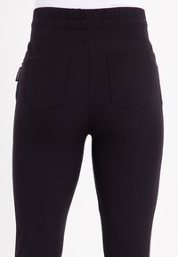 Zwarte stretchbroek met een hoge elastische tailleband, voorzien van twee achterzakken en een slanke, gladde textuur.