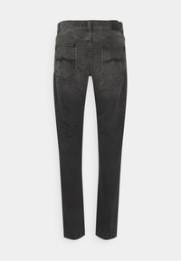 Tmavě šedé džíny s úzkým střihem, které mají dvě zadní kapsy a jemné švy podél okrajů kapes.