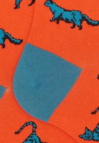 Calzini arancioni con un motivo di gatti blu, con punta e tallone rinforzati di colore blu solido. Realizzati in materiale liscio ed elastico.